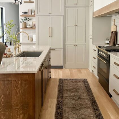 Small painted kitchen. Cabinets in light gray paint. Box hood painted white with stained brown accent that matches the stained island.