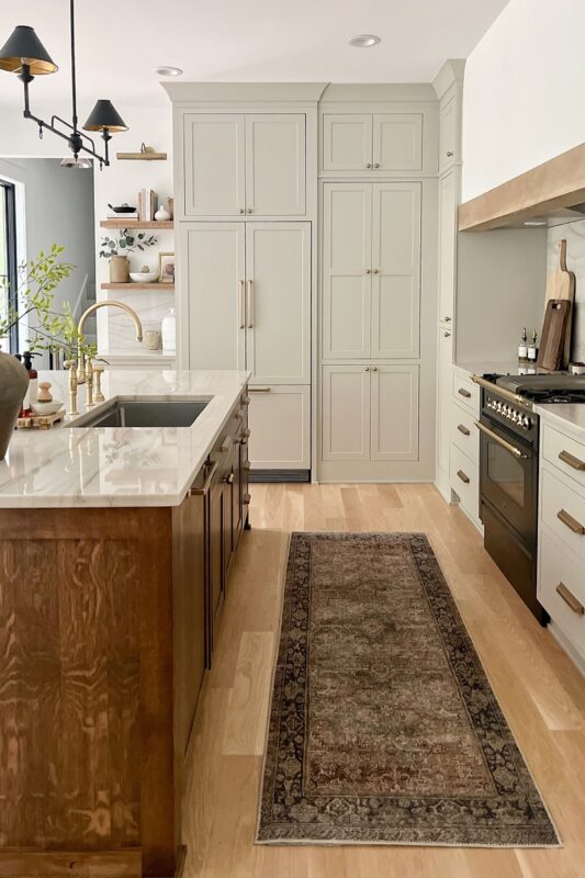 Small painted kitchen. Cabinets in light gray paint. Box hood painted white with stained brown accent that matches the stained island.