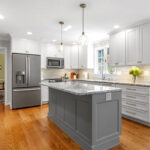 White-painted kitchen perimeter cabinets with a gray-painted island.