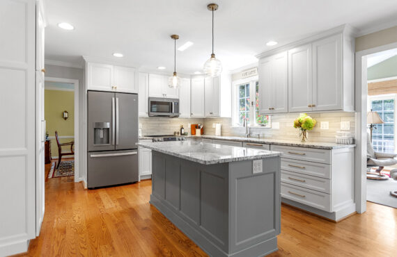 White-painted kitchen perimeter cabinets with a gray-painted island.