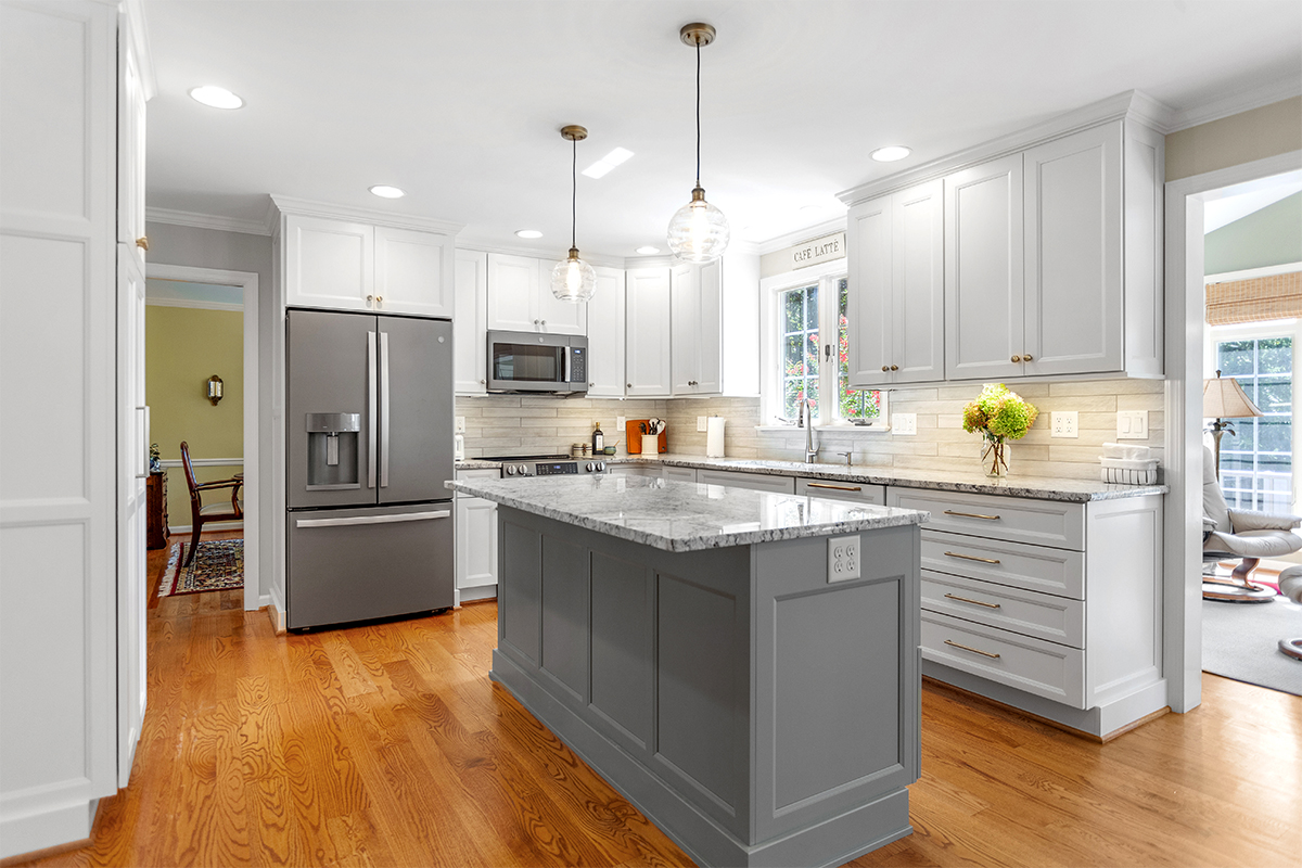 White-painted kitchen perimeter cabinets with a gray-painted island.