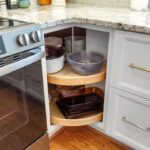 White painted kitchen cabinets with doors and drawers open to show internal storage accessories.