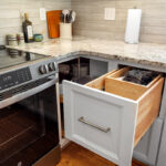 White painted kitchen cabinets with doors and drawers open to show internal storage accessories.