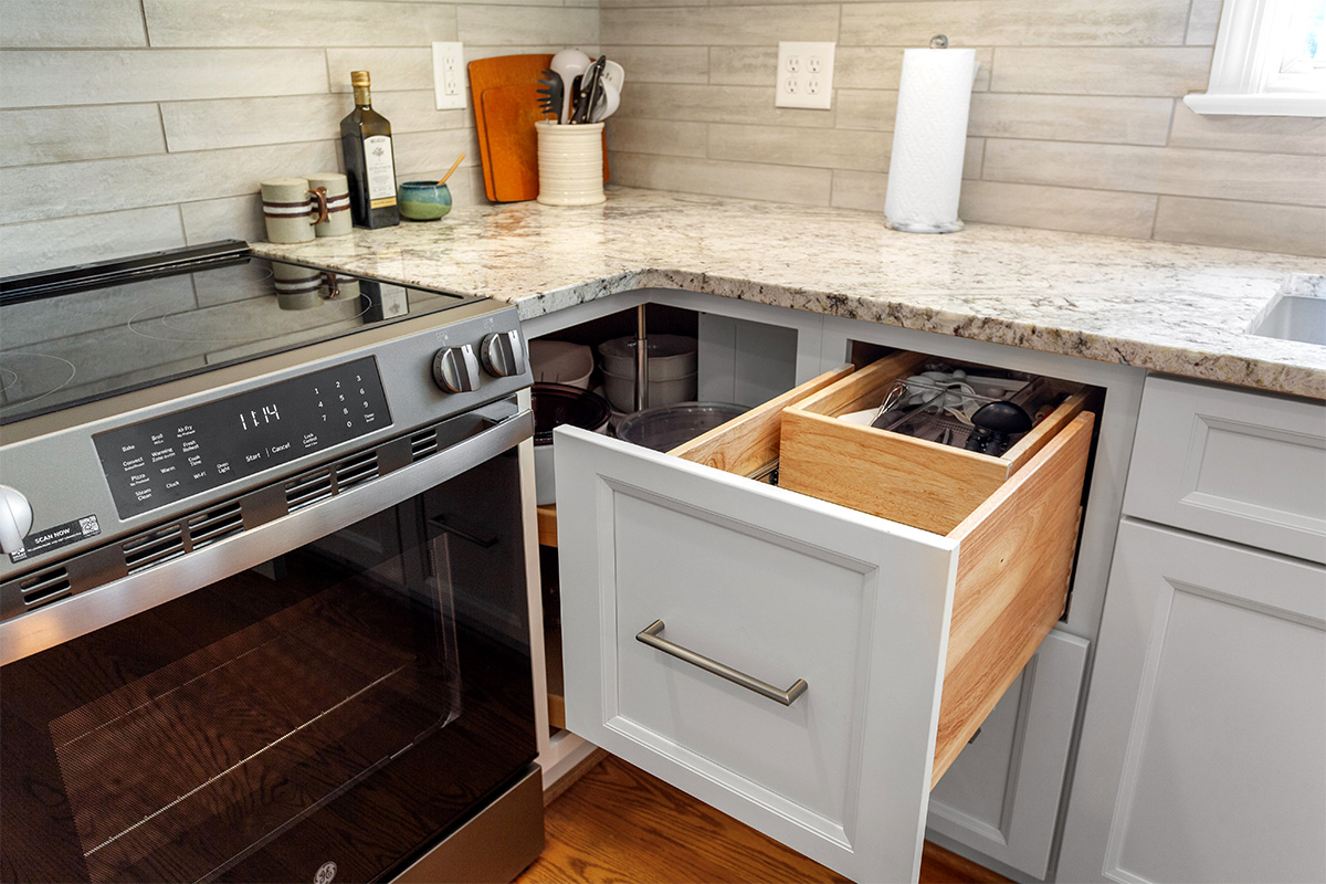 White painted kitchen cabinets with doors and drawers open to show internal storage accessories.
