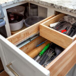 White painted kitchen cabinets with doors and drawers open to show internal storage accessories.
