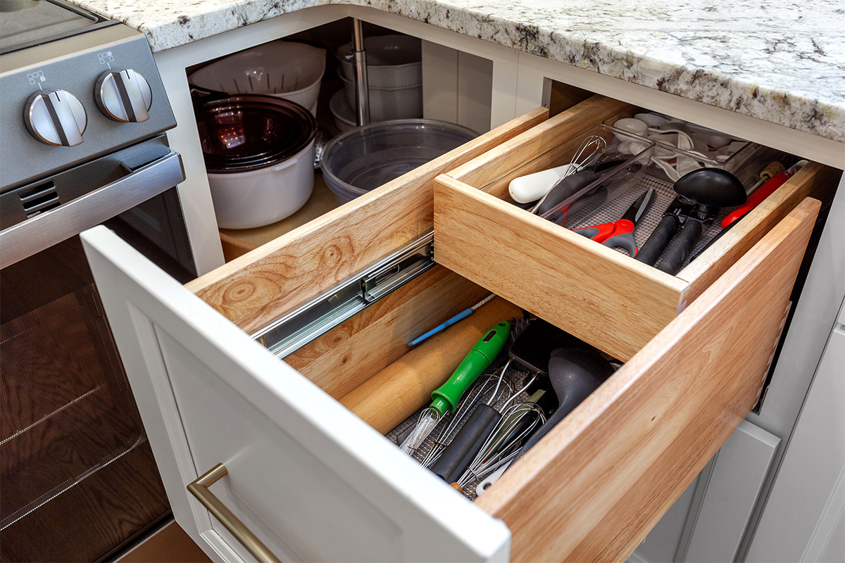 White painted kitchen cabinets with doors and drawers open to show internal storage accessories.