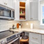 White painted kitchen cabinets with doors and drawers open to show internal storage accessories.