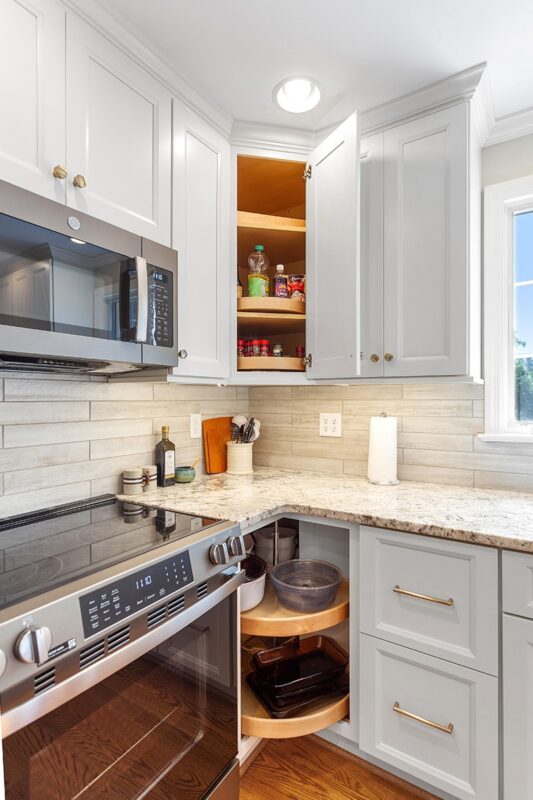 White painted kitchen cabinets with doors and drawers open to show internal storage accessories.