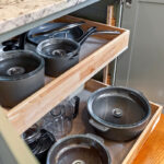 White painted kitchen cabinets with doors and drawers open to show internal storage accessories.