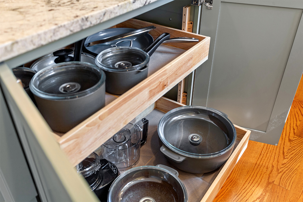White painted kitchen cabinets with doors and drawers open to show internal storage accessories.