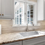 White-painted kitchen cabinets with a window over the sink