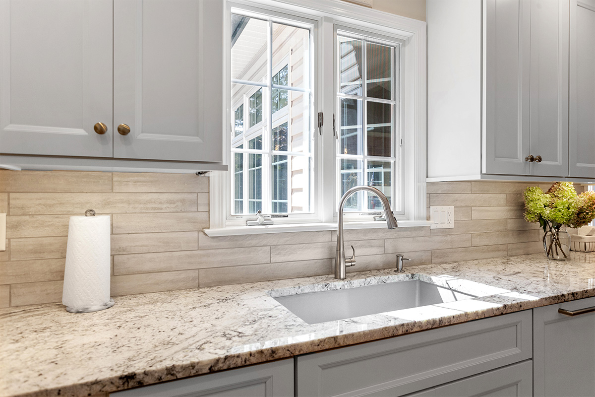 White-painted kitchen cabinets with a window over the sink