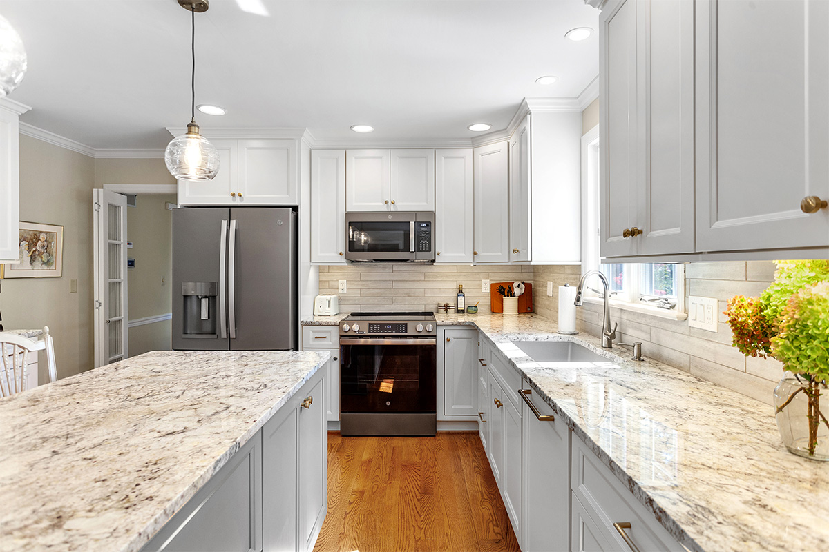 White-painted kitchen perimeter cabinets with a gray-painted island.