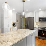 White-painted kitchen perimeter cabinets with a gray-painted island.