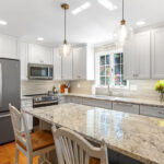 White-painted kitchen perimeter cabinets with a gray-painted island.