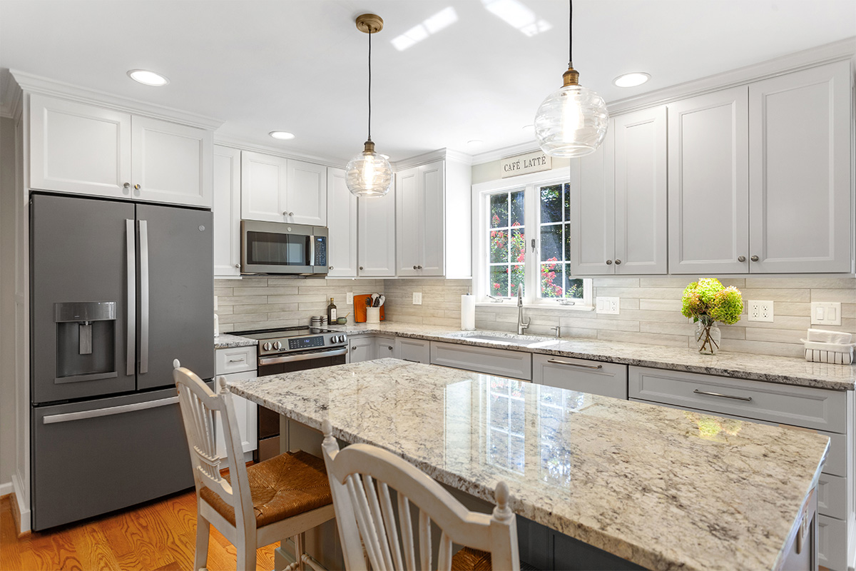 White-painted kitchen perimeter cabinets with a gray-painted island.
