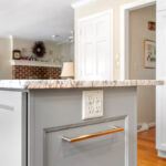 White-painted kitchen perimeter cabinets with a gray-painted island.