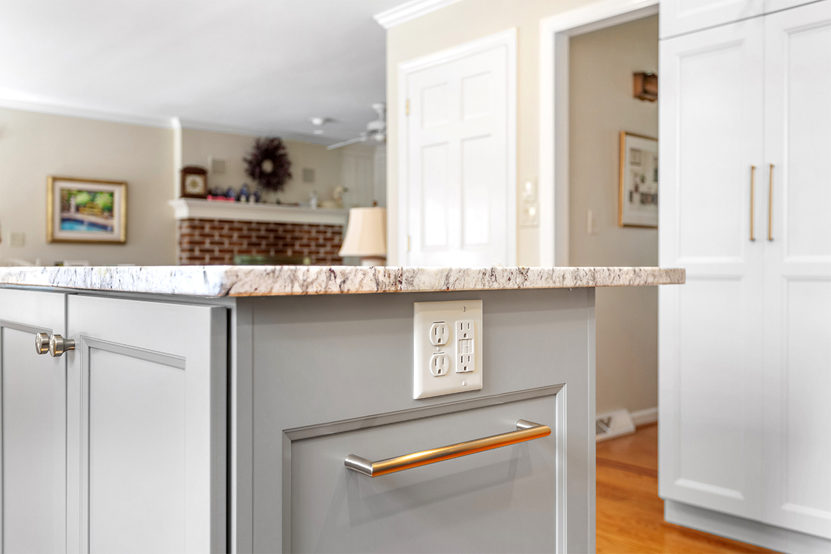 White-painted kitchen perimeter cabinets with a gray-painted island.