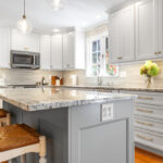 White-painted kitchen perimeter cabinets with a gray-painted island.