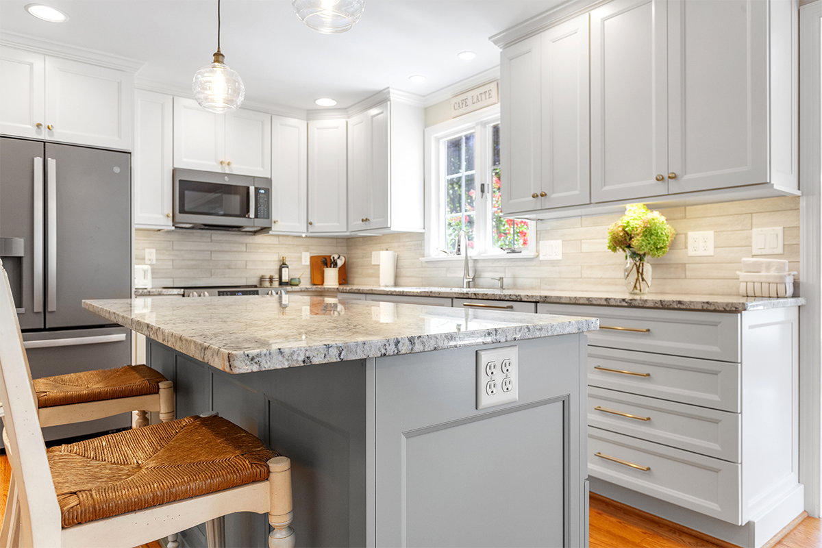 White-painted kitchen perimeter cabinets with a gray-painted island.