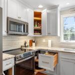 White painted kitchen cabinets with doors and drawers open to show internal storage accessories.
