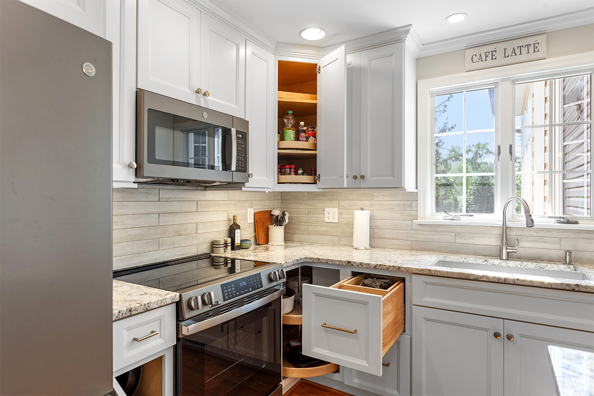 White painted kitchen cabinets with doors and drawers open to show internal storage accessories.