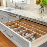 White painted kitchen cabinets with doors and drawers open to show internal storage accessories.