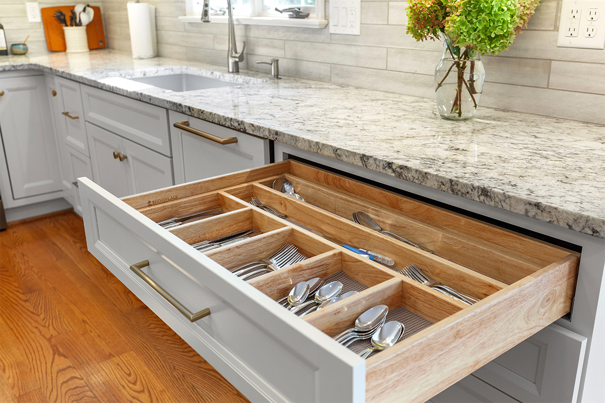 White painted kitchen cabinets with doors and drawers open to show internal storage accessories.