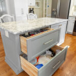 White-painted kitchen perimeter cabinets with a gray-painted island.