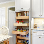White painted kitchen cabinets with doors and drawers open to show internal storage accessories.
