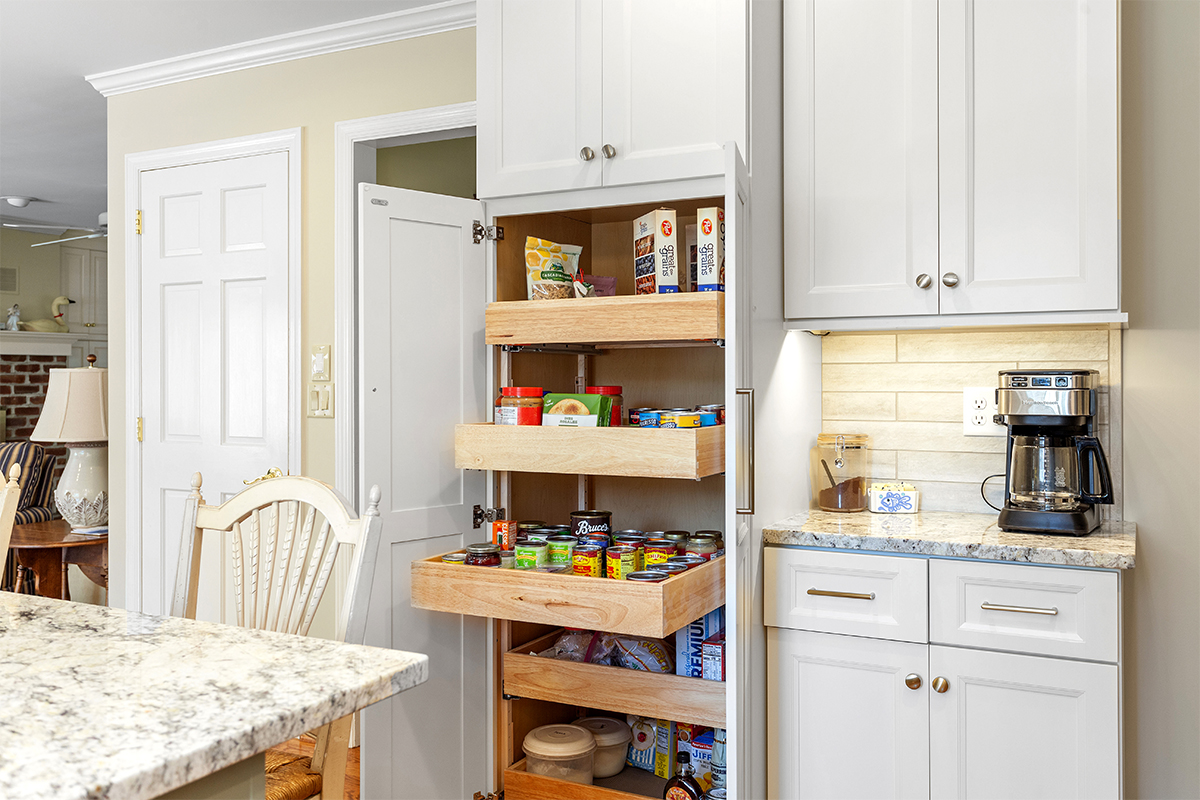 White painted kitchen cabinets with doors and drawers open to show internal storage accessories.