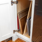 White painted kitchen cabinets with doors and drawers open to show internal storage accessories.