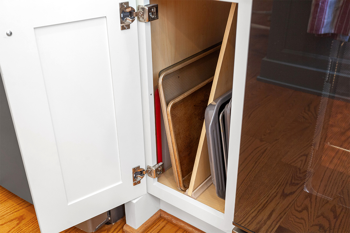 White painted kitchen cabinets with doors and drawers open to show internal storage accessories.