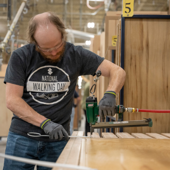 Man attaching a hanging hook to a panel to be run through the finish booth