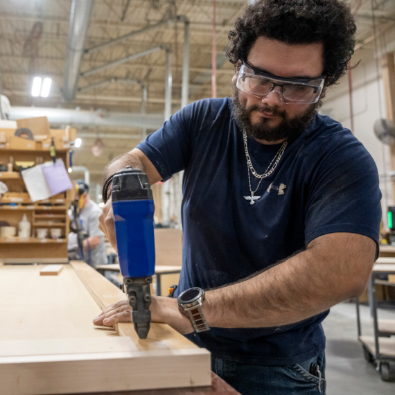 Man attaching bracing to the bottom of a wood top.