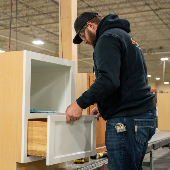 Man installing drawer into base cabinet