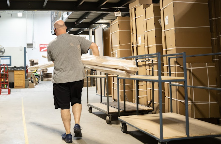 Man carrying a bunch of molding pieces in a warehouse.