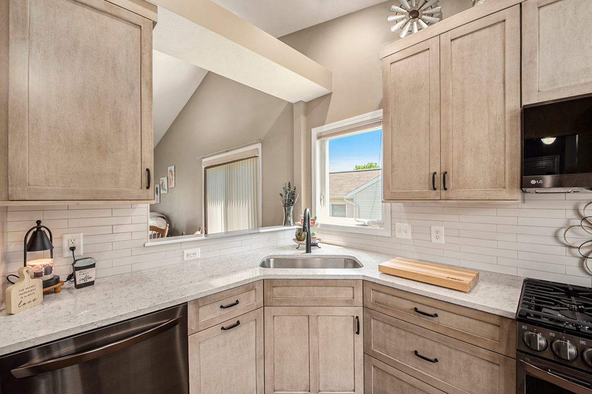 Light stained kitchen cabinets with black appliances.