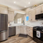 Light stained kitchen cabinets with black appliances.