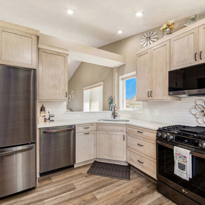 Light stained kitchen cabinets with black appliances.