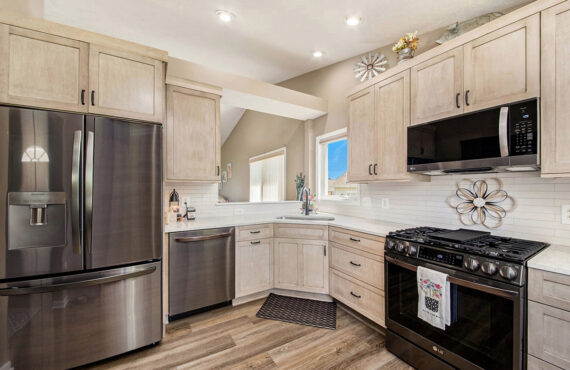 Light stained kitchen cabinets with black appliances.