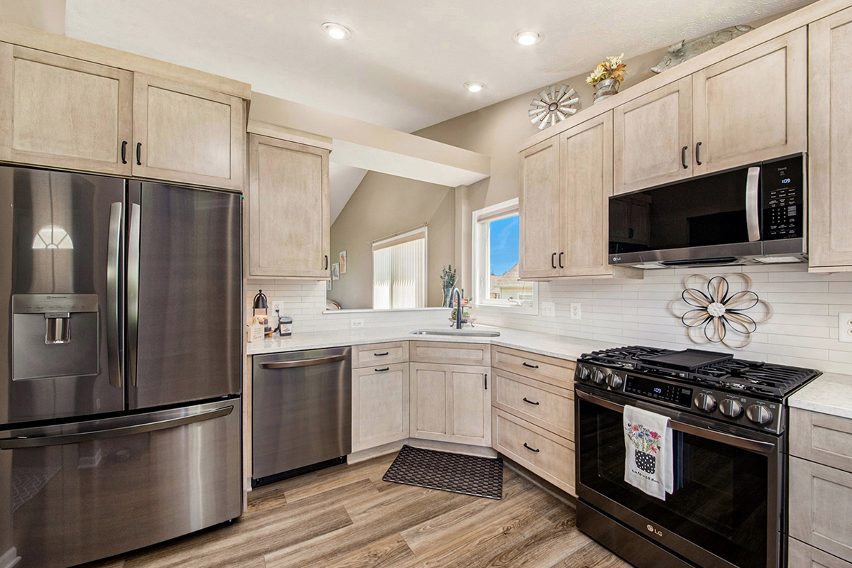 Light stained kitchen cabinets with black appliances.