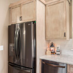 Light stained kitchen cabinets with black appliances.