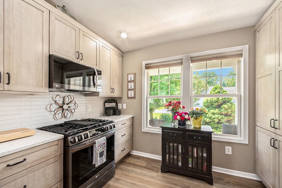 Light stained kitchen cabinets with black appliances.