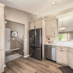 Light stained kitchen cabinets with black appliances.