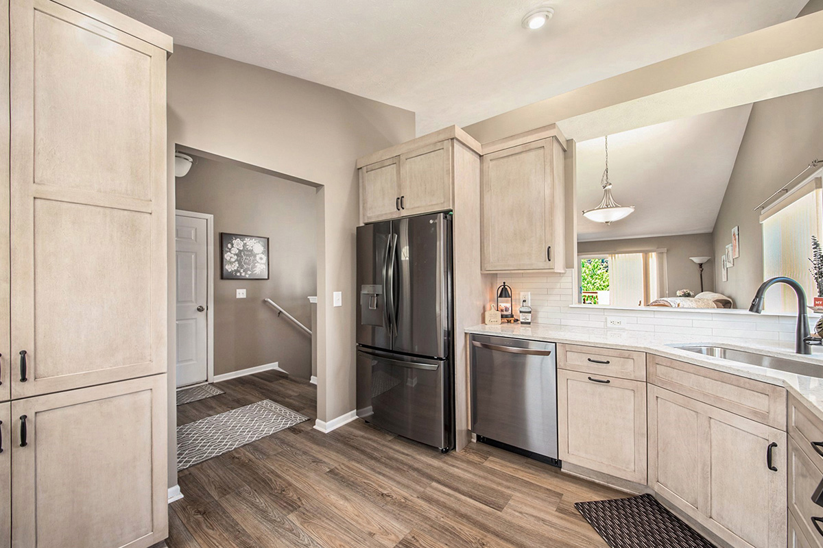 Light stained kitchen cabinets with black appliances.