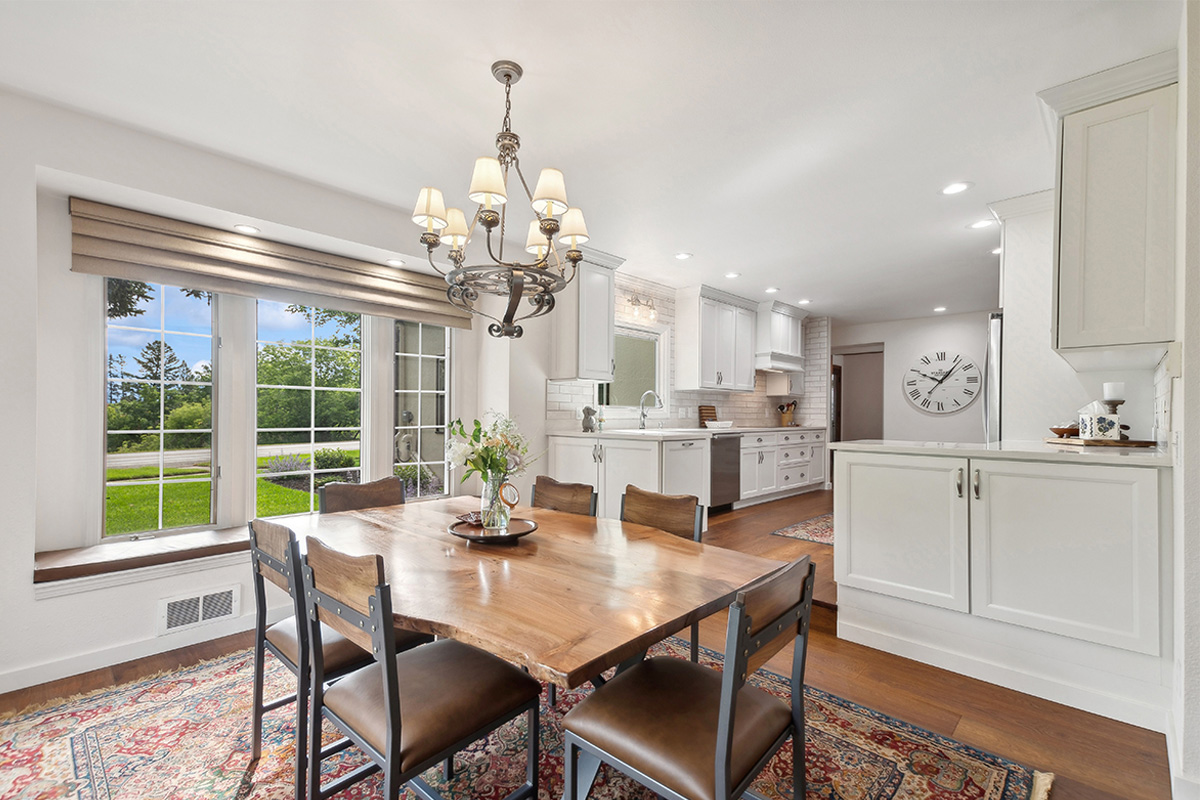 Dining room with table looking towards a white painted kitchen with wood floors