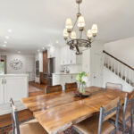 Dining room with table looking towards a white painted kitchen with wood floors