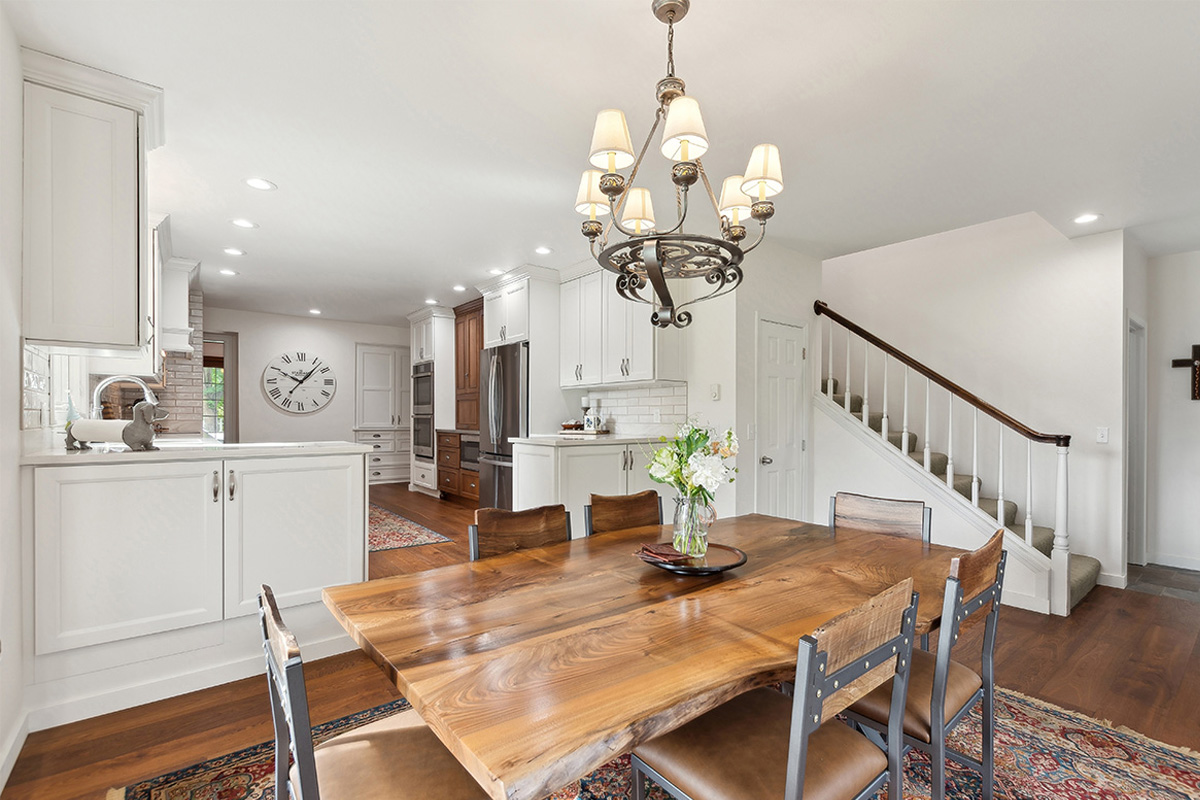 Dining room with table looking towards a white painted kitchen with wood floors