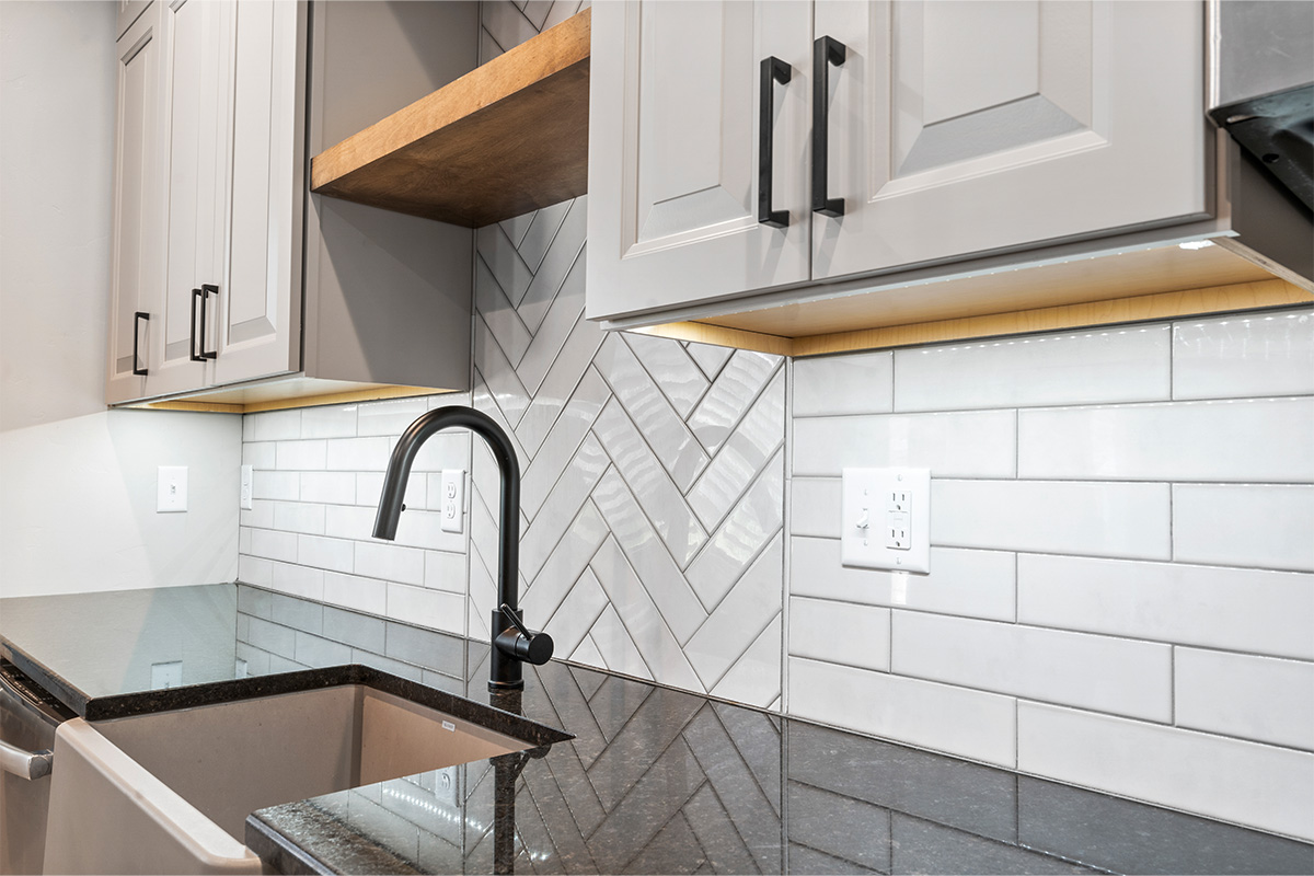 Gun Smoke painted kitchen cabinets with view of sink and tile backsplash